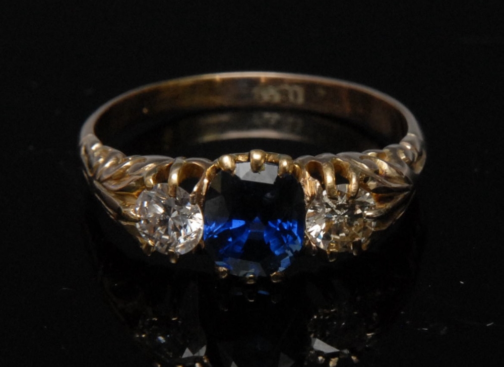 A diamond and sapphire three stone ring, oval central blue sapphire approx. 1.72ct, flanked by two