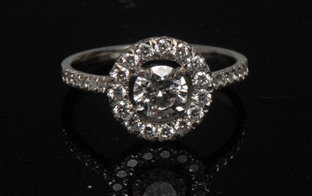 A diamond cluster ring, central brilliant cut diamond approx. 0.53ct, claw set within an open band