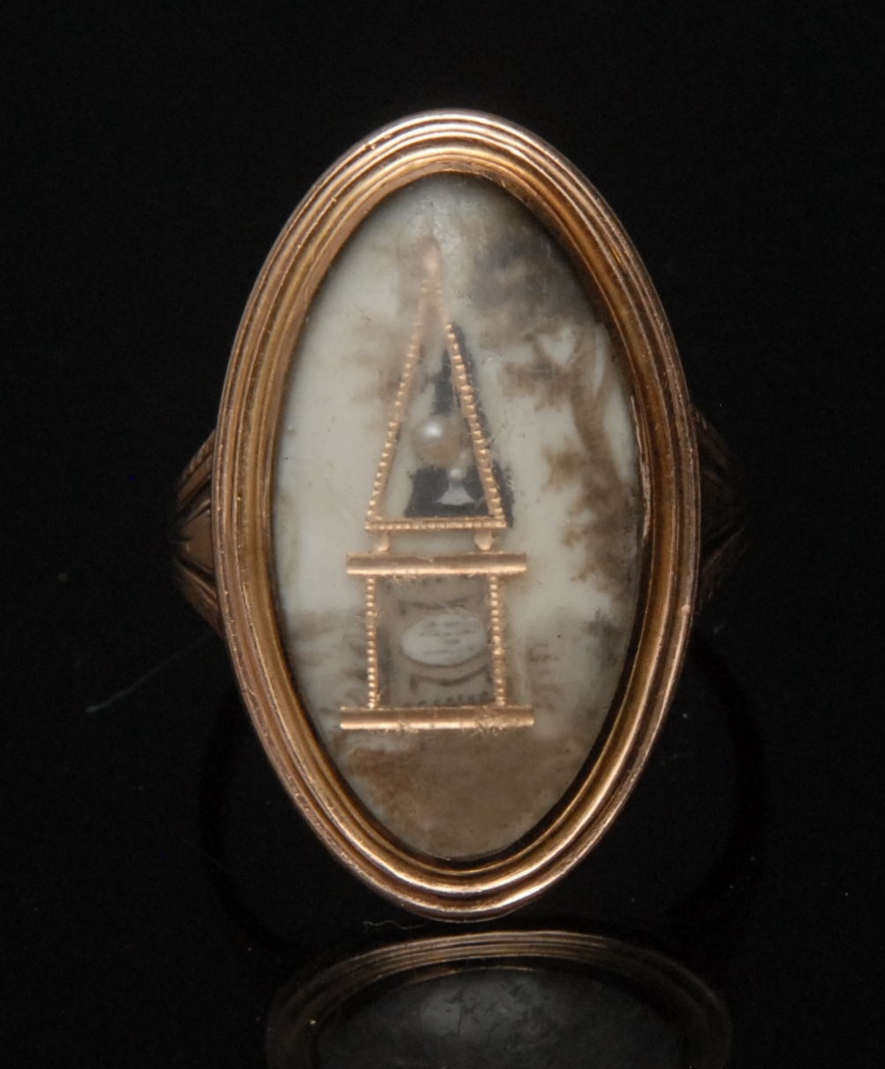 A George III oval mourning ring,  decorated with a single seed pearl set filigree obelisk in
