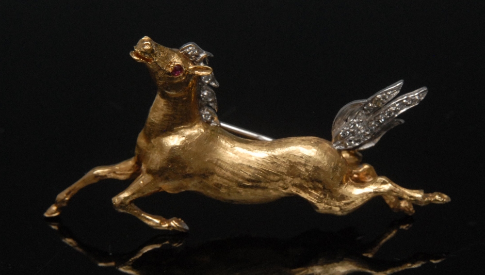 A diamond and ruby galloping horse brooch, 18ct yellow gold body, ruby eye, white gold mane and tail