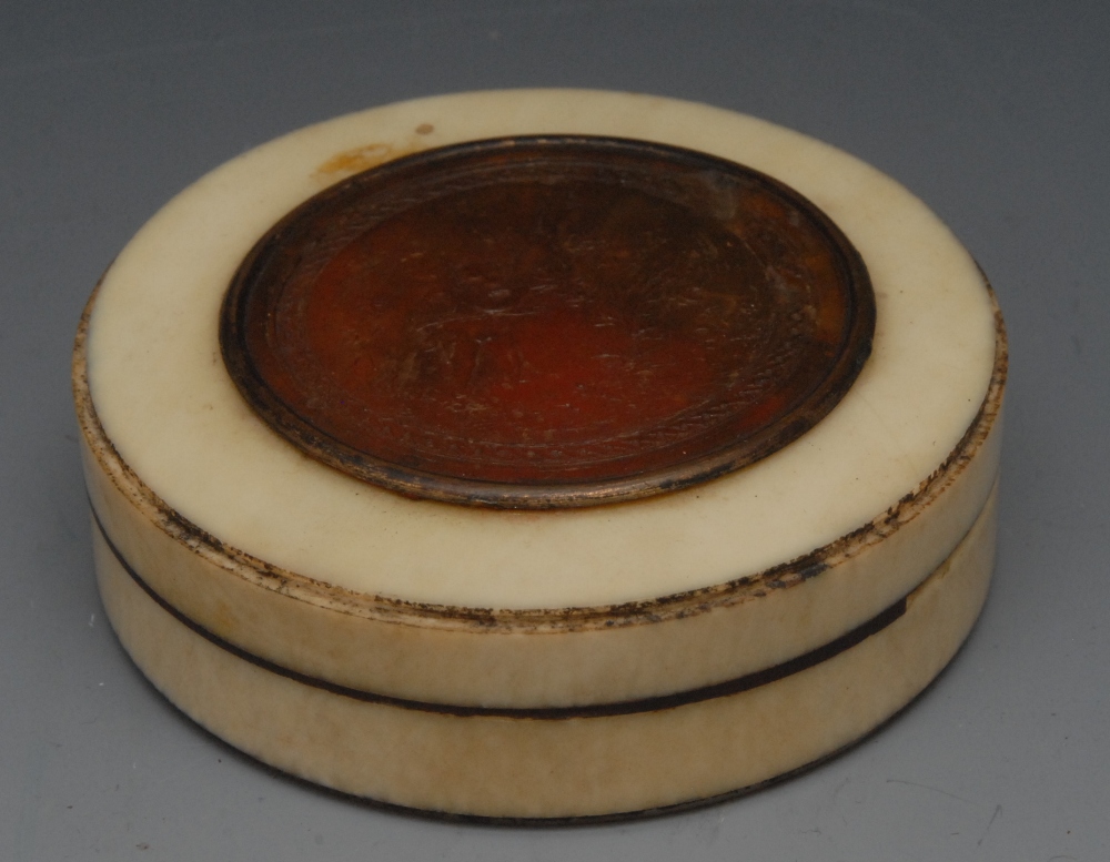 A 19th century circular ivory and pressed horn snuff box, the cover with circular panel with Cupid