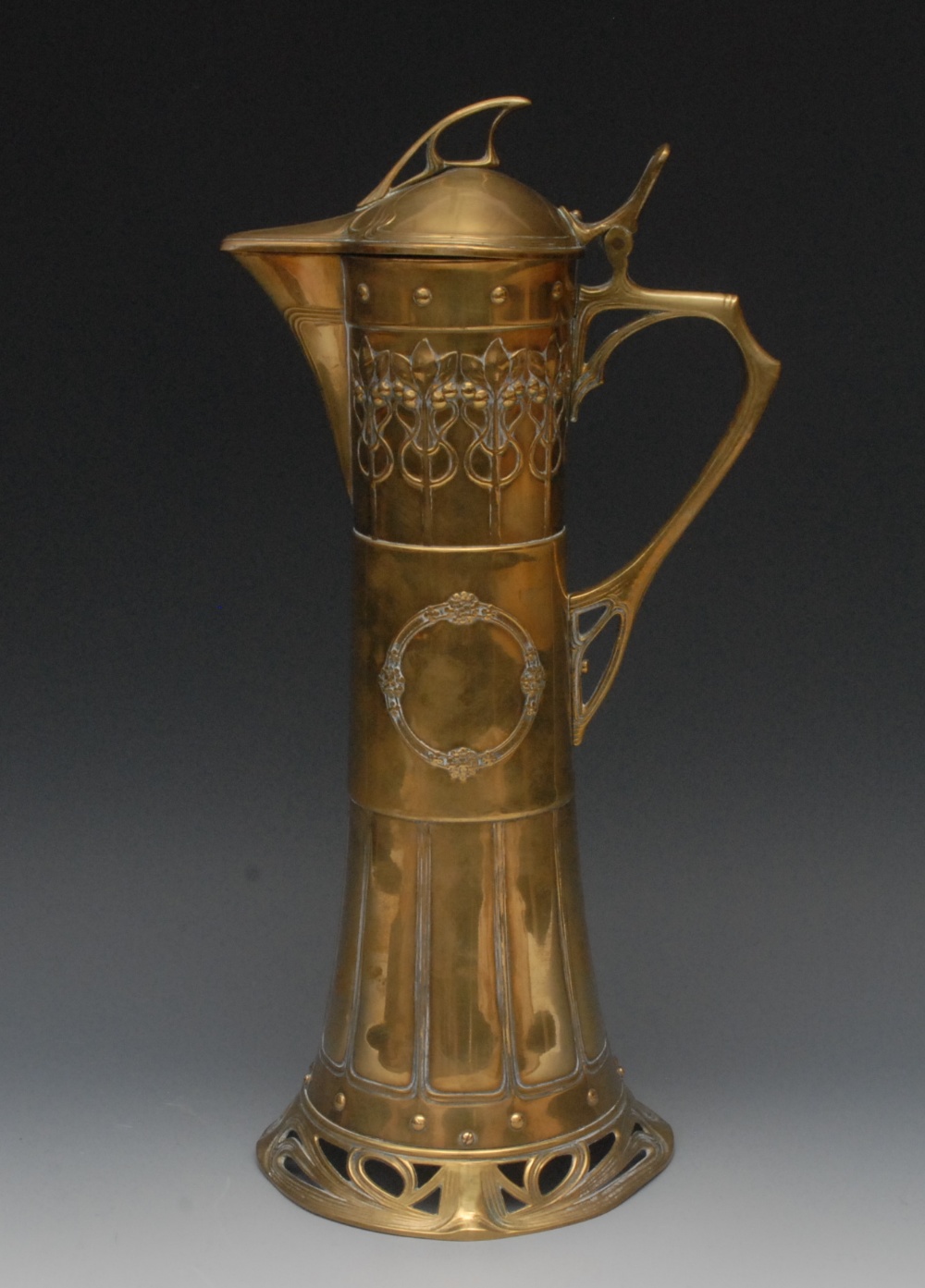 A W.M.F. Jugendstil brass wine jug, cast with roundel and stylised foliage, pierced scroll base,