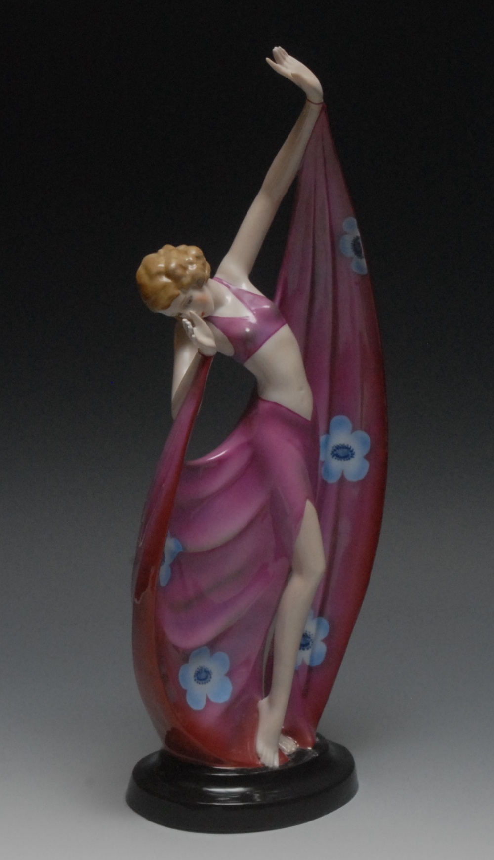 An Art Deco Continental model, of a dancing girl, with pink flowing dress with blue flowers, black