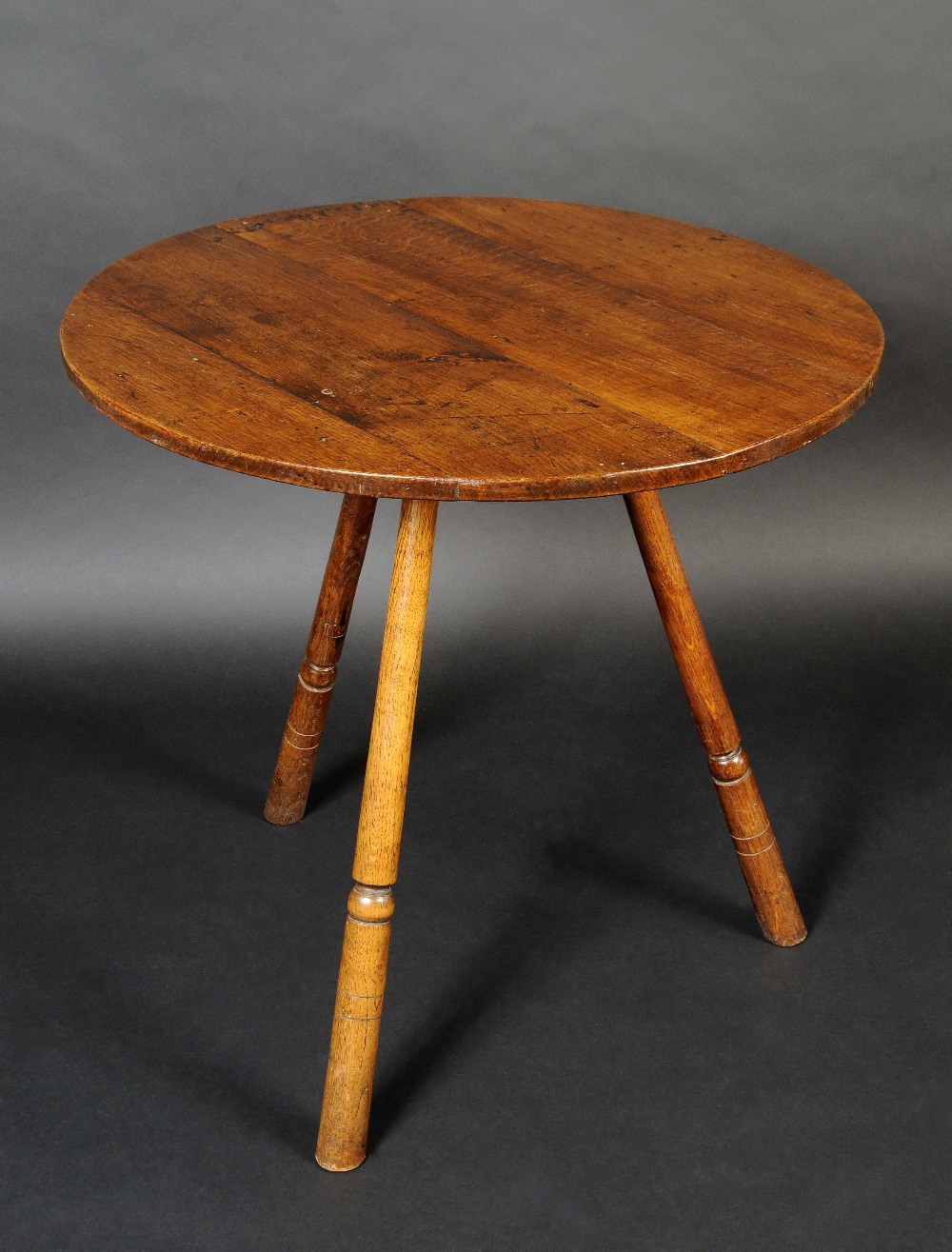A 19th century oak cricket table, circular planked top, turned outswept legs, 73cm high, 74.5cm