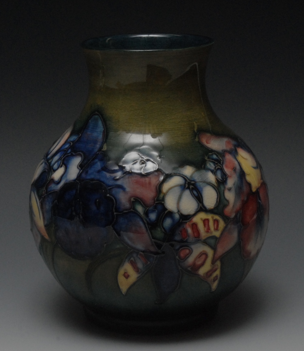 A Moorcroft Blue Iris pattern ovoid vase, tube lined with colourful flowers, on a mottled green