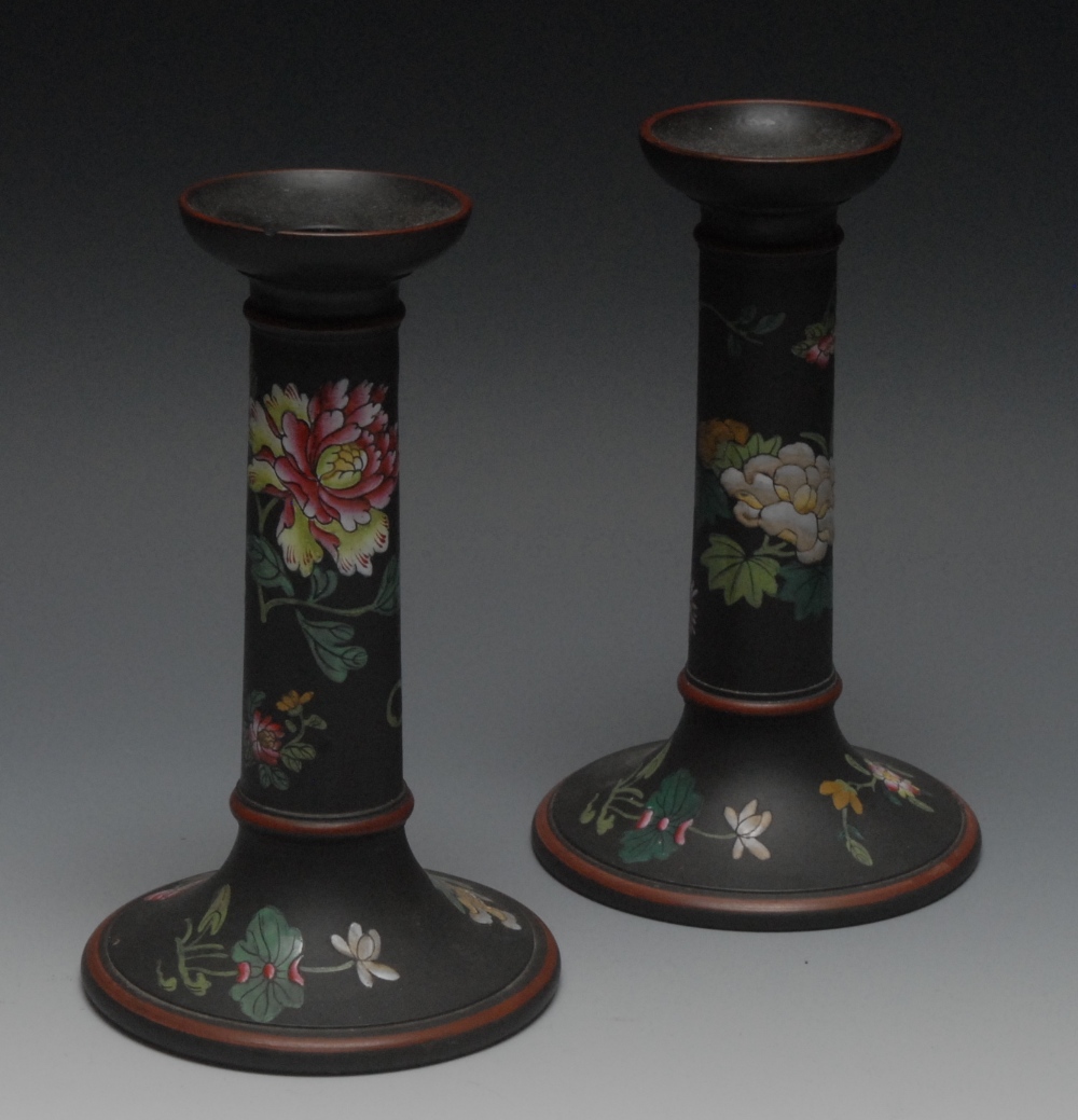 A pair of Wedgwood table candlesticks, decorated in coloured enamels with stylised flowers and
