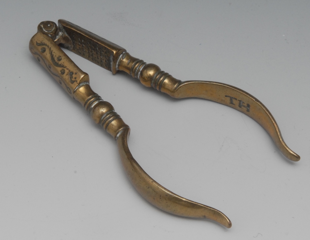A pair of Queen Anne brass nut crackers, of typical form, terminals engraved with feathering
