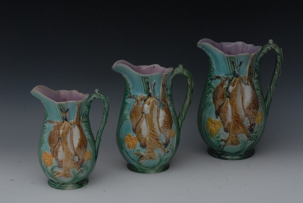 A set of three Victorian majolica Game jugs, in relief with hanging game, in tones of brown,