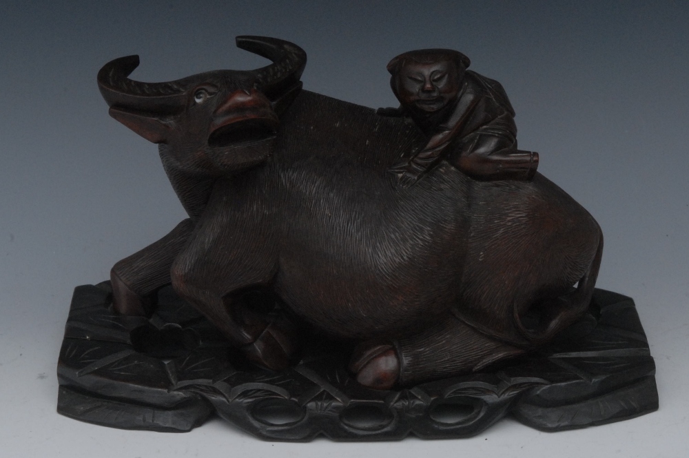 A Chinese hardwood carving, of a boy riding on the back of a buffalo, hardwood base, 25cm wide, c.
