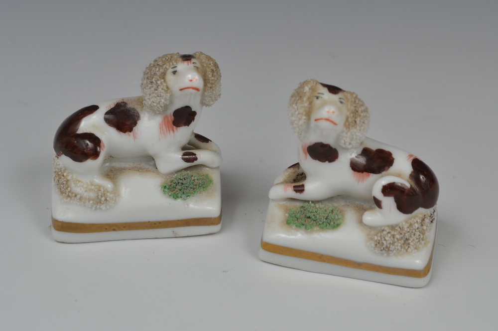 A pair of miniature porcelaneous  Staffordshire spaniels, seated to the left and right, applied with