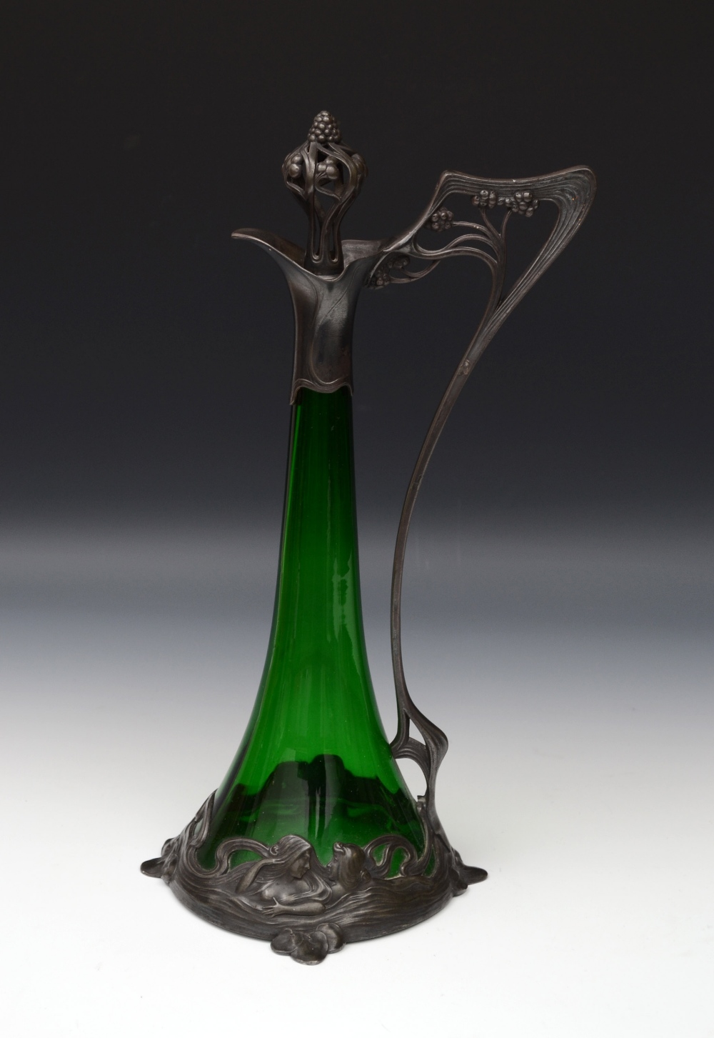 A W.M.F.Art Nouveau green glass inverted trumpet shaped claret jug, the mount in relief with young