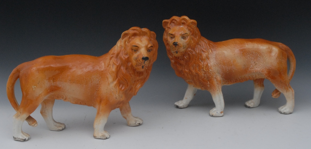 A pair of 19th century Staffordshire models, of lions, standing to left and right, 25cm high, 33cm