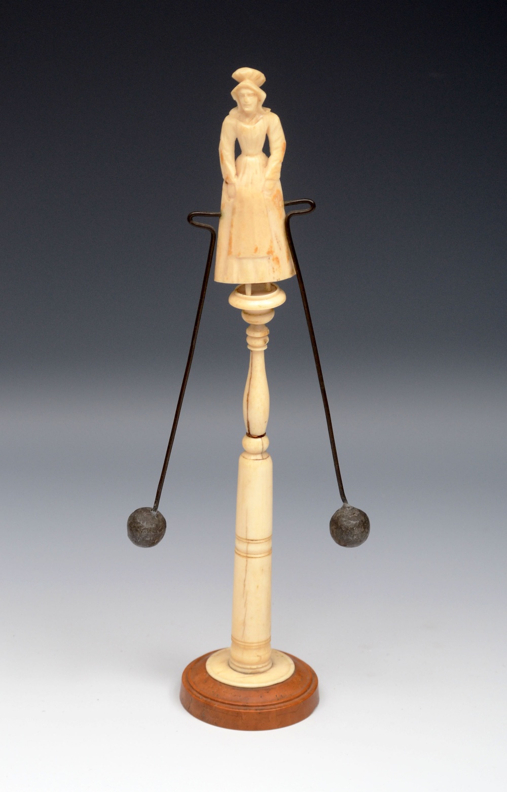 A Continental ivory novelty balancing toy, probably French, carved as a woman in a cloth cap, atop