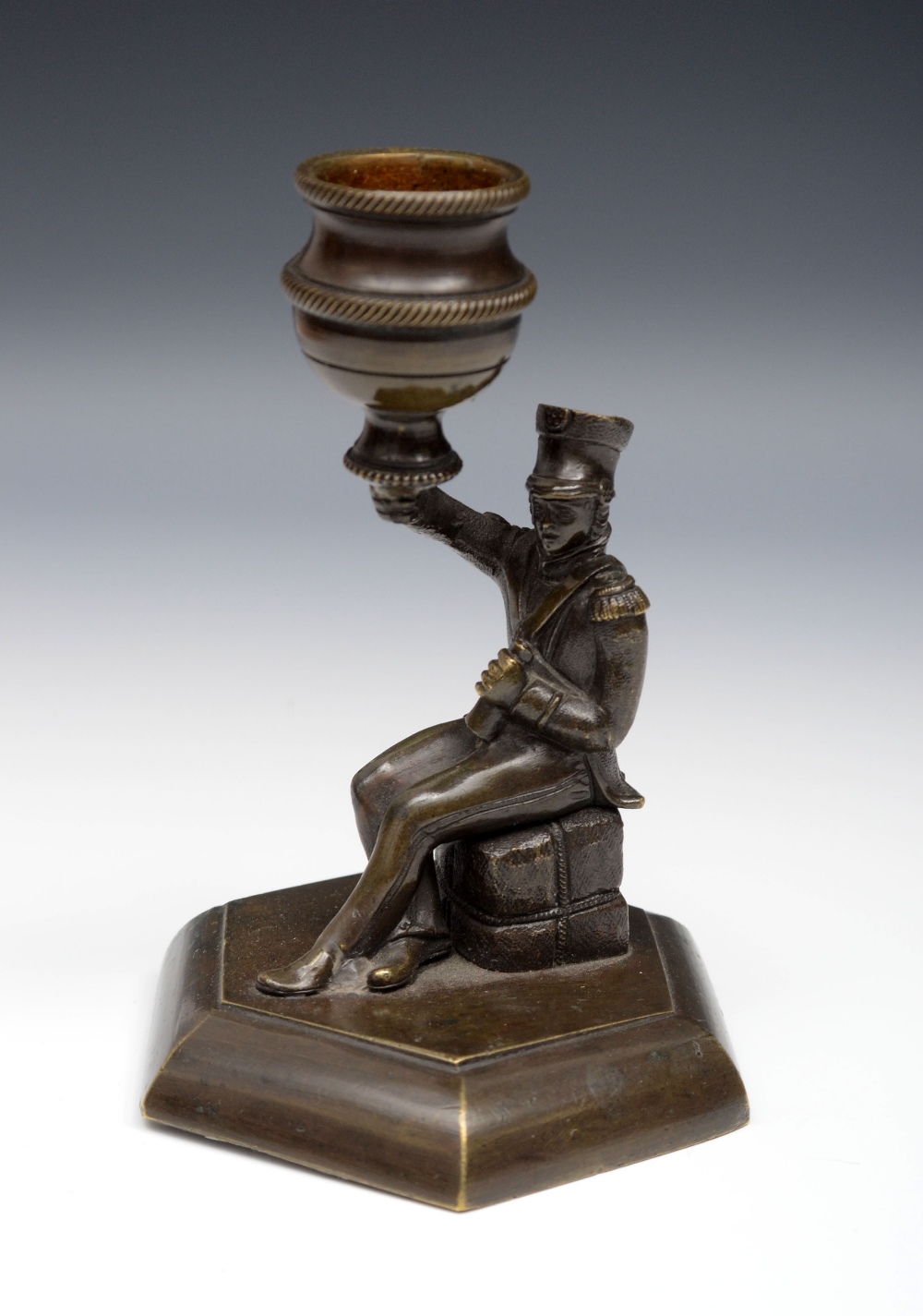 A 19th century patinated bronze novelty candlestick, the sconce supported by an infantry officer,