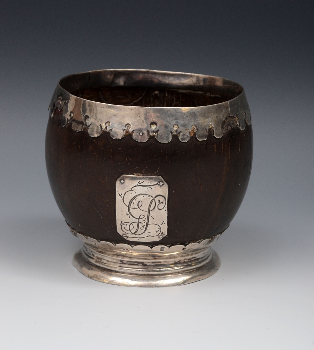 A George III silver coloured metal mounted coconut cup, applied with a canted rectangular