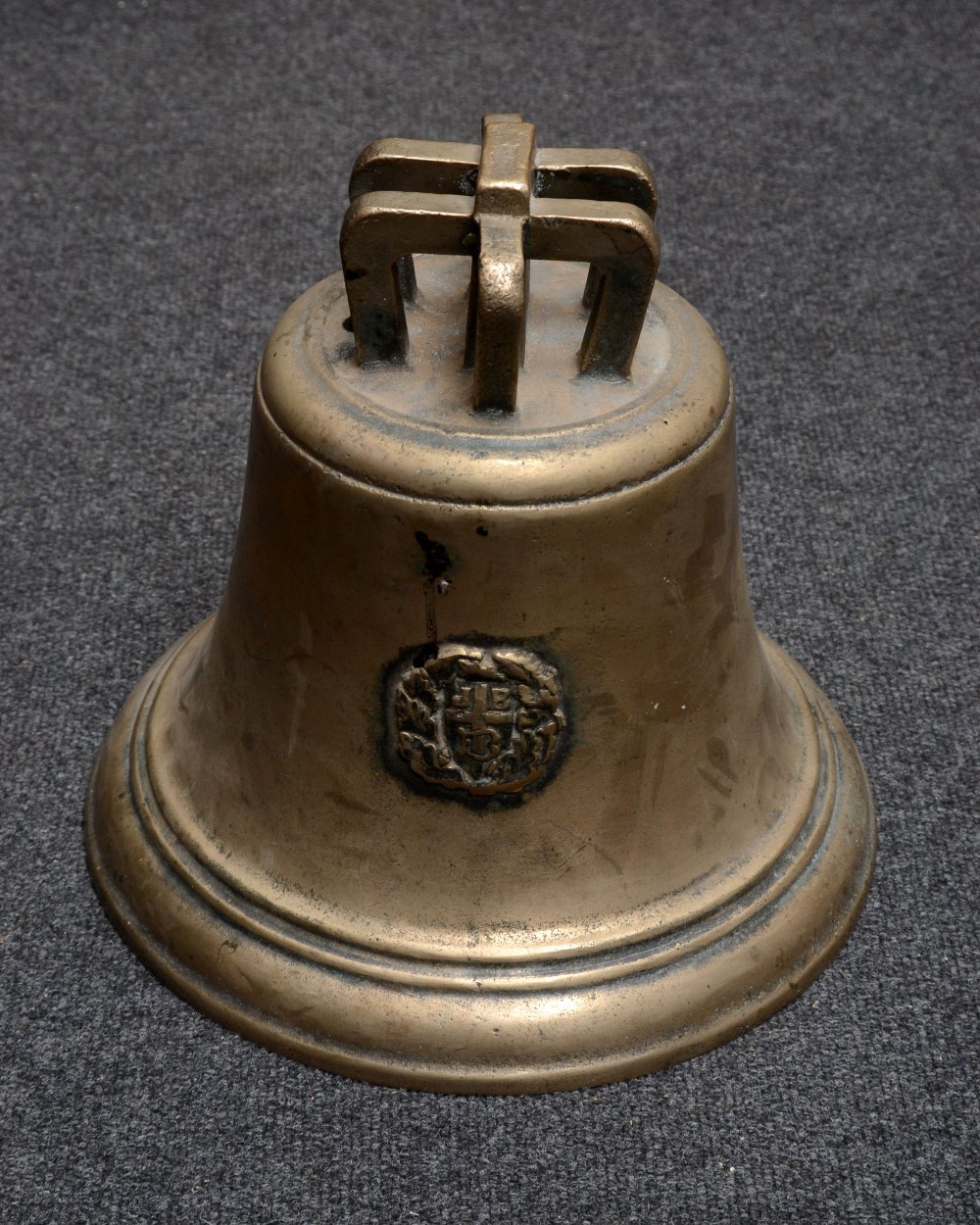 A bronze bell, cast with seal initialled JB with a cross within a wreath, 31cm high