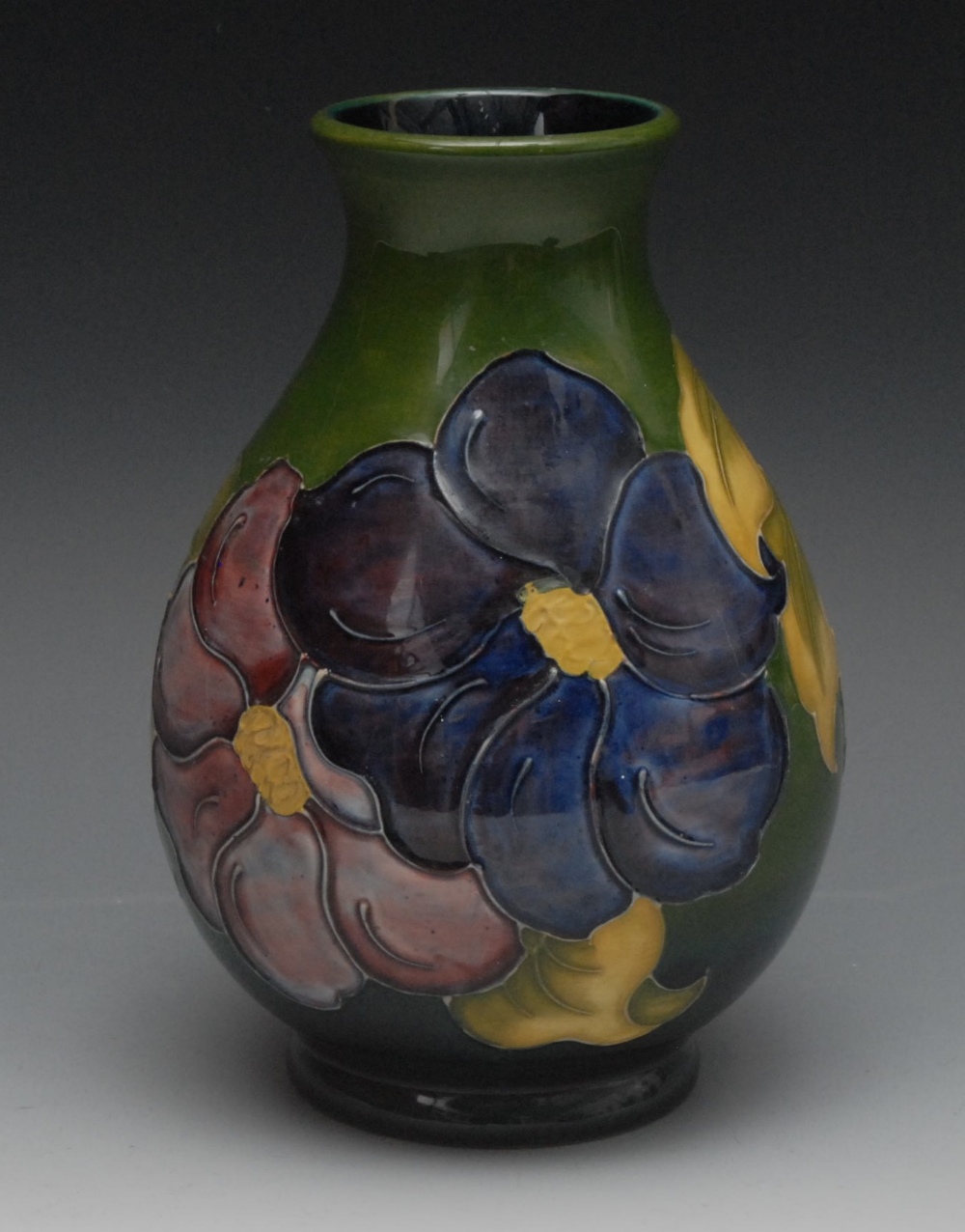 A Moorcroft Clematis pattern vase, tube lined with large flowers and foliage, on a green ground,