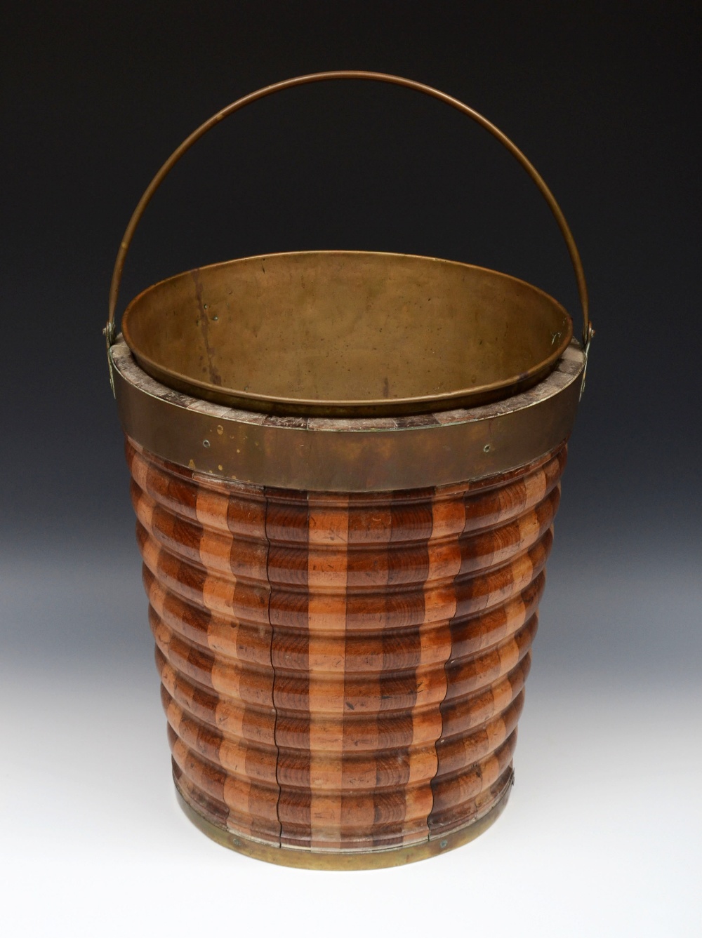 A 19th century Dutch brass bound staved fruitwood ribbed and tapered bucket, swing handle, brass