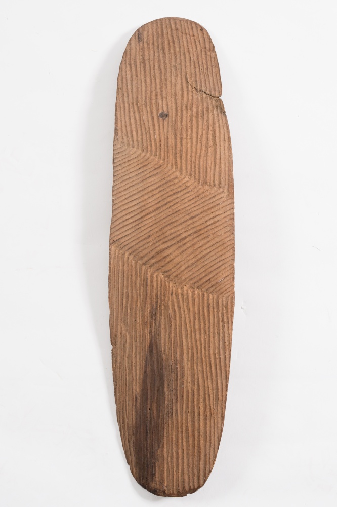 An Aboriginal wooden hand shield: of rectangular form with rounded ends having broad incised line