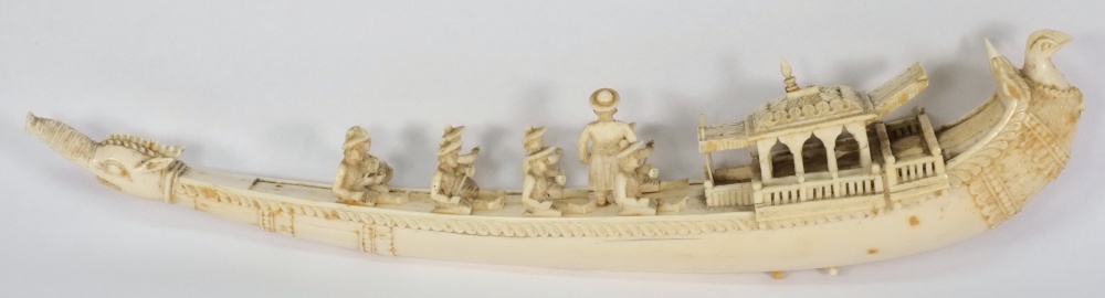 A carved ivory ceremonial barge:  with eight seated oarsmen, with carved animal head bow and bird'