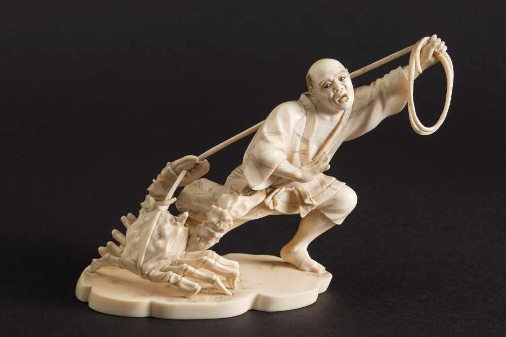 A Japanese carved ivory okimono depicting a fisherman being attacked by a crab: signed Seikyu to the