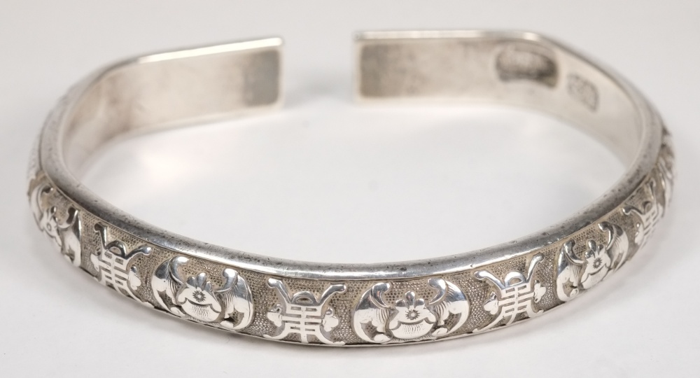 A Chinese silver bangle: decorated with stylised bats and prunus blossom, bears finesse marks, 2.