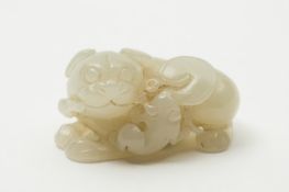 A Chinese jade carving of a reclining mythical beast: a lizard and lotus  plant to one side of it`s