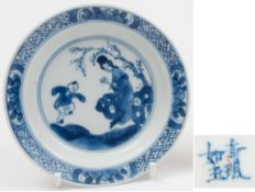 A Chinese blue and white saucer: with flared rim, painted with a dancing boy, his mother seated