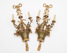 A pair of gilt brass basket three-light wall appliques: the semi-round lattice work baskets