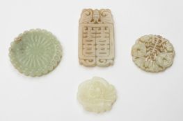 A group of four Chinese celadon jade pendants: one in the form of a  flowerhead, 7cm; one carved