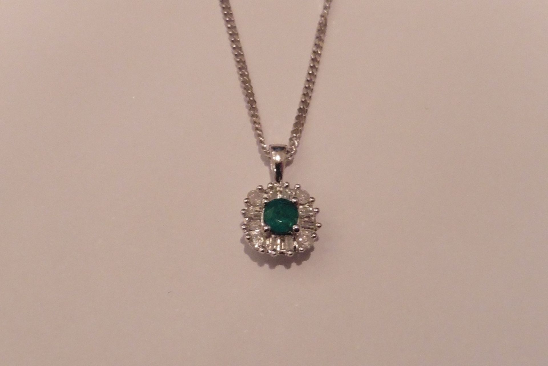 9ct white gold emerald and diamond pendant set with a round cut emerald which is surrounded with tap