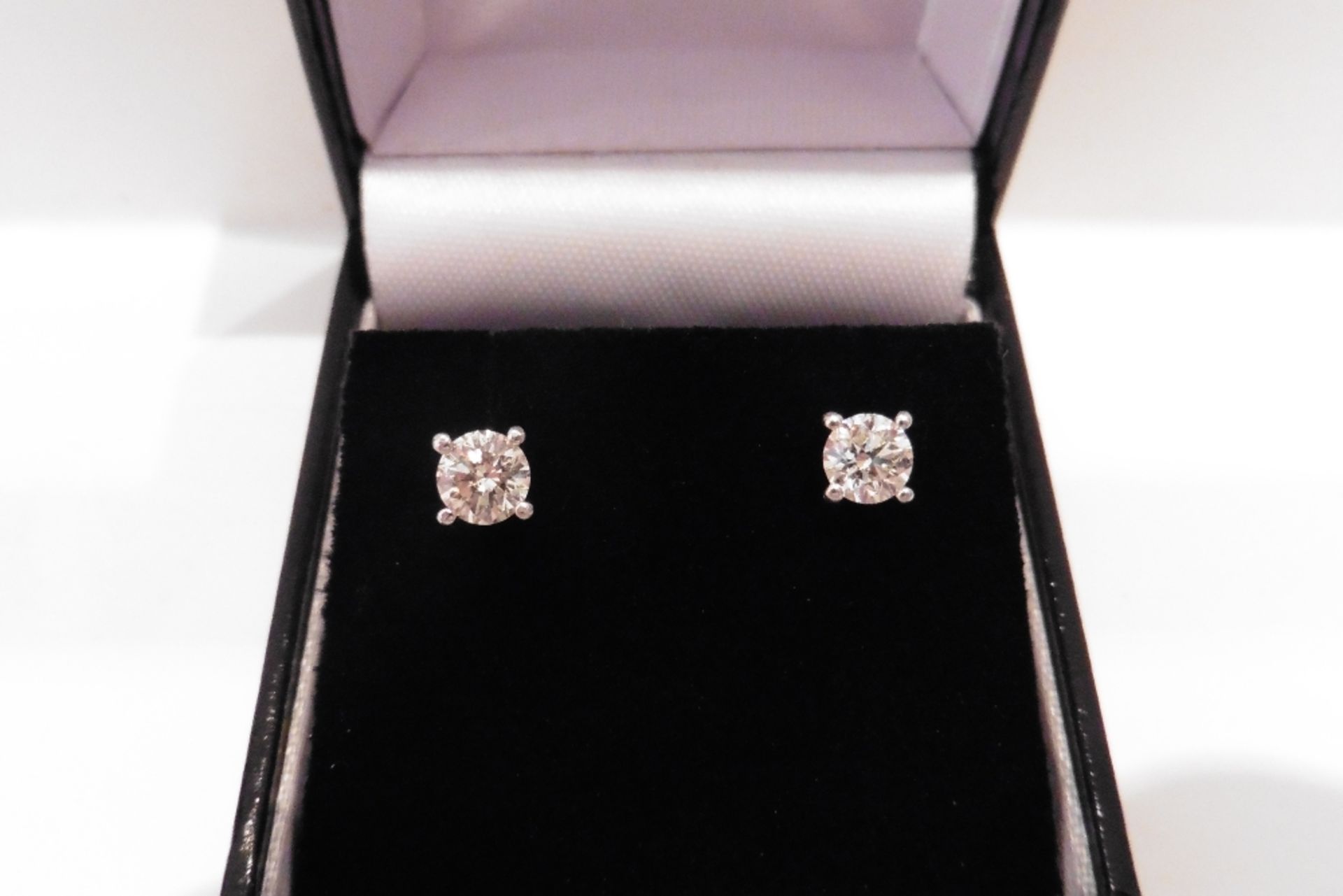 Pair of solitaire stud earrings each set with a russian cut diamond weighing a total of 0.18ct. Grad