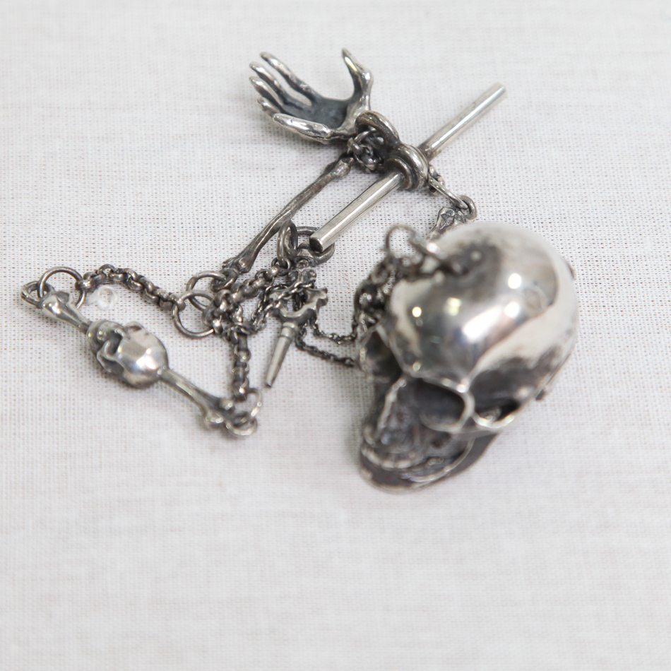 Macabre silver watch chain hung with a skull and bones etc.