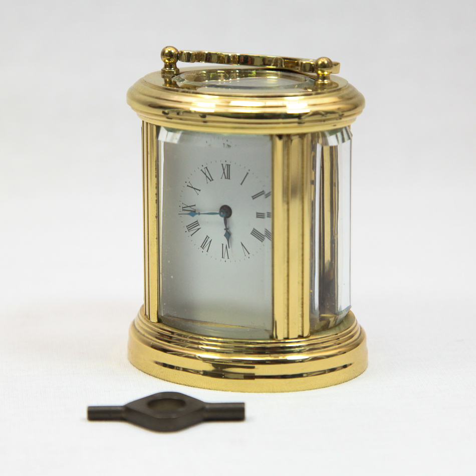 Oval brass and glass case small carriage clock, 11 cm high, complete with key
