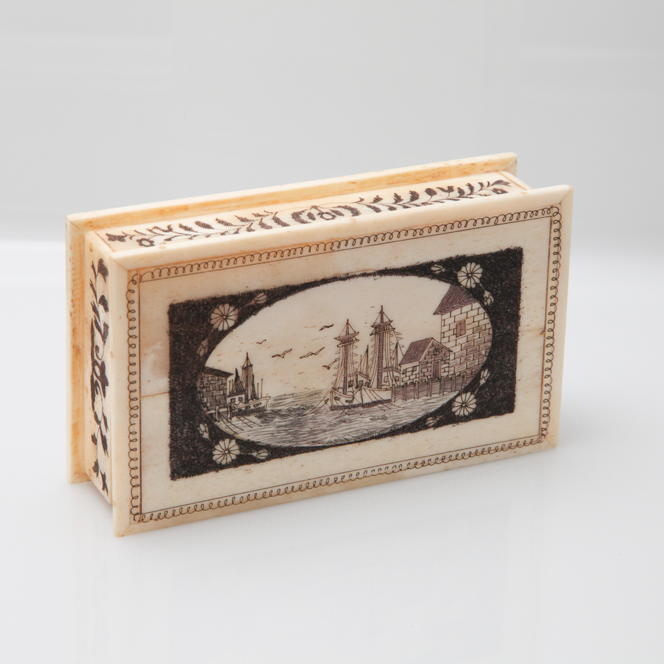 Rectangular bone box with engraved scrimshaw style decoration depicting ships in a harbour