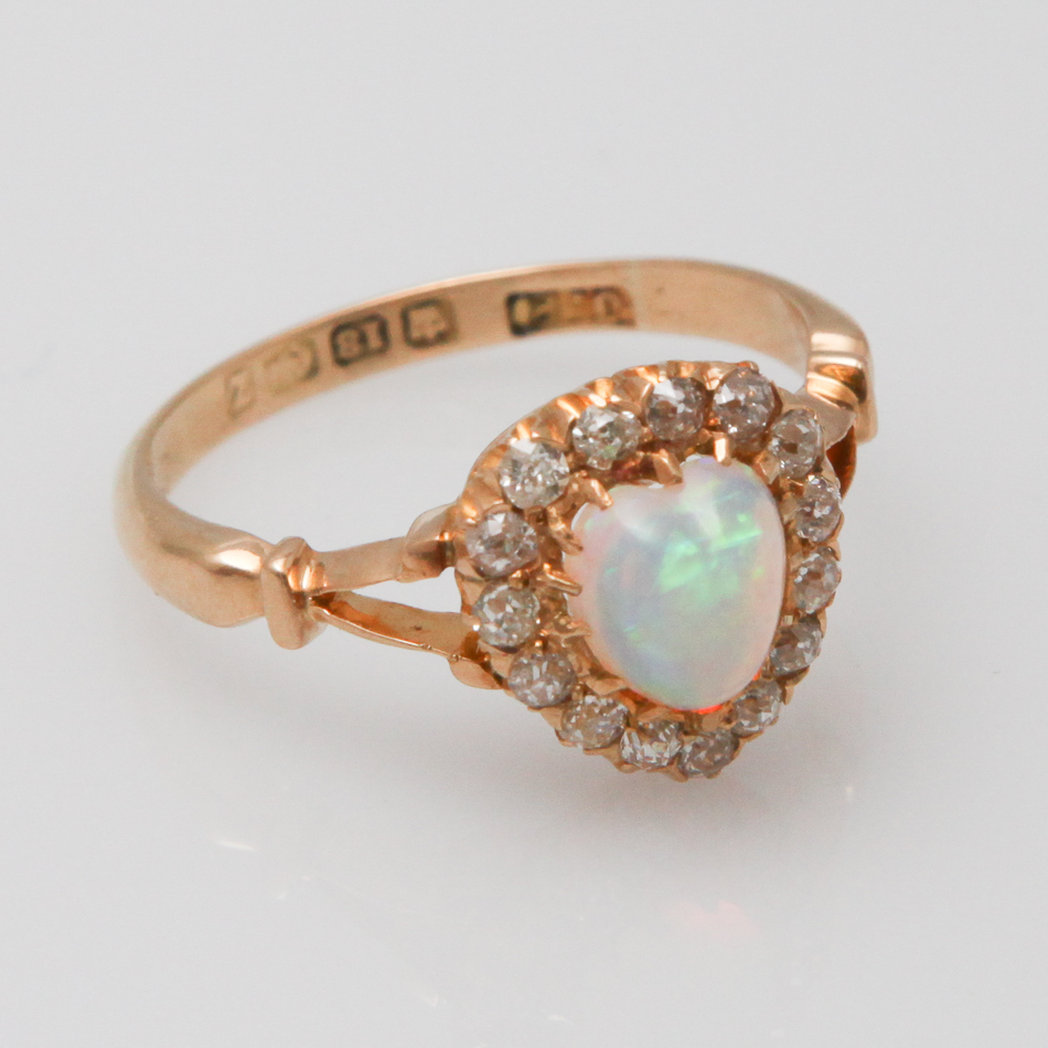 A Victorian 18ct gold ring, set with a central  heart shaped opal surrounded by diamonds, to open