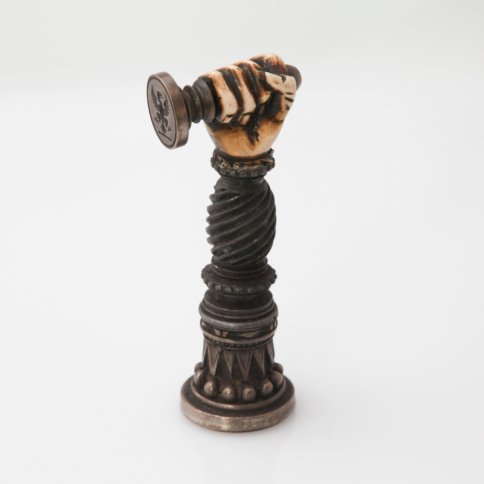Pewter double ended desk seal modelled as an arm with carved bone hand, 7 cm high