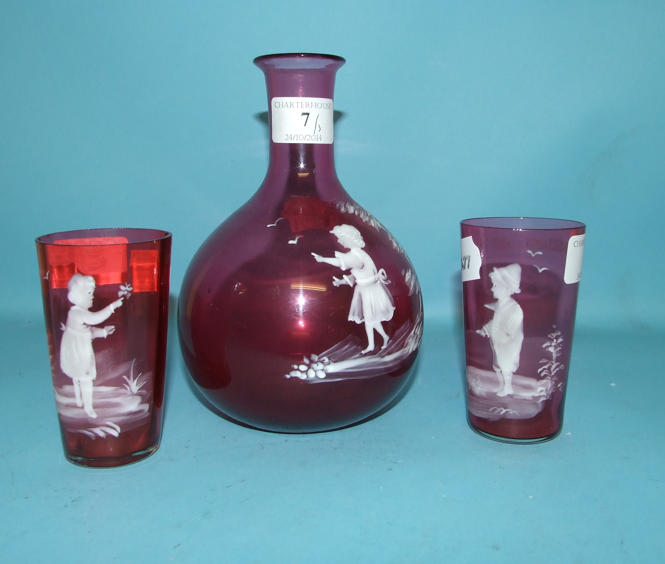 A Mary Gregory style cranberry glass decanter, with a matching pair of tumblers (3)