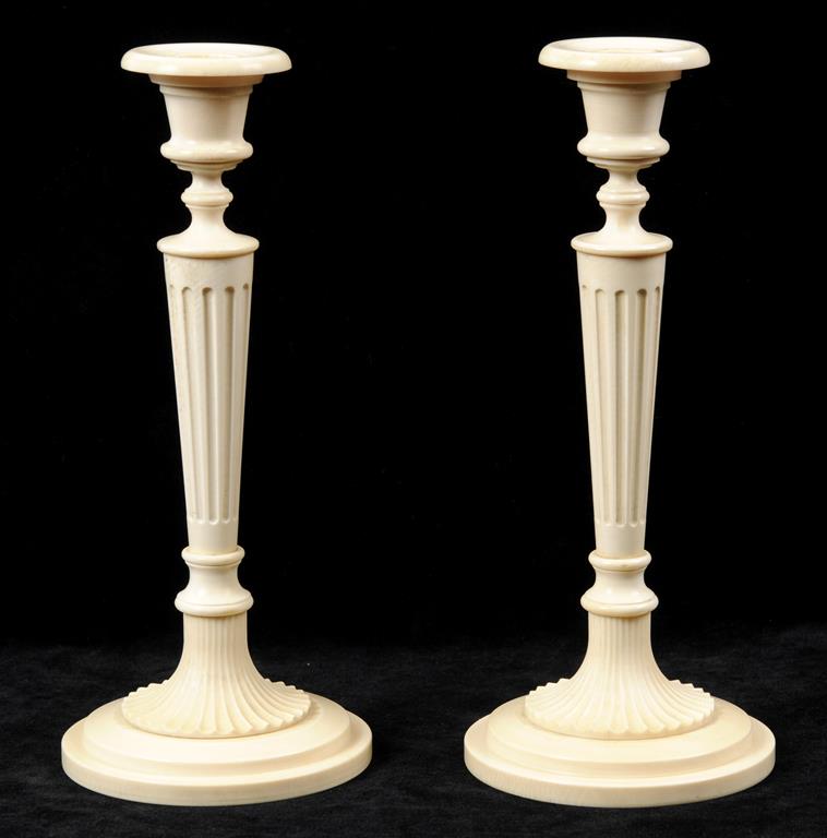 A pair of ivory candlesticks, with fluted columns, and spreading circular bases, 23 cm high (2)  See