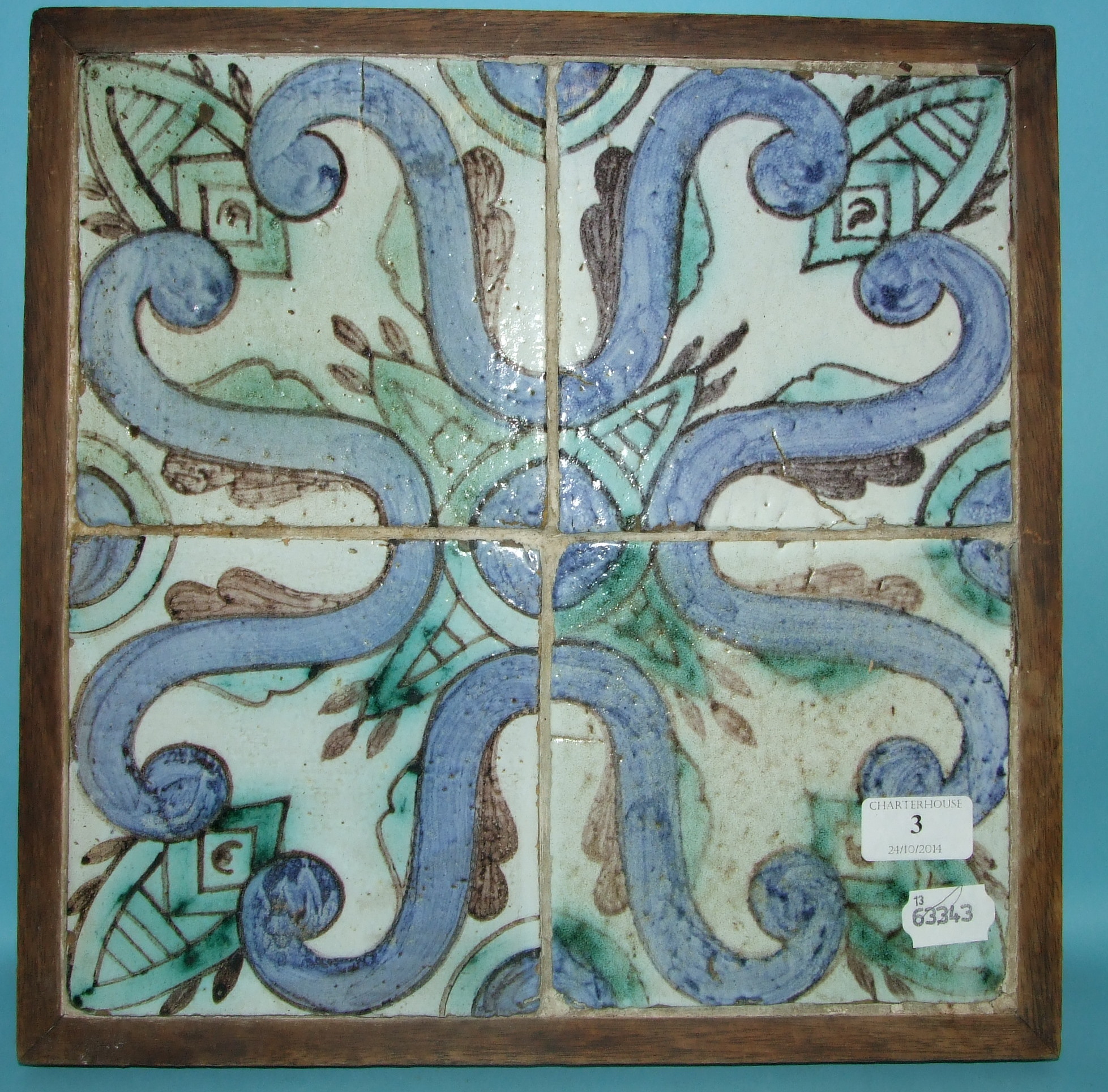 A set of four tiles, with scroll decoration, framed as one, each 15.5 cm square