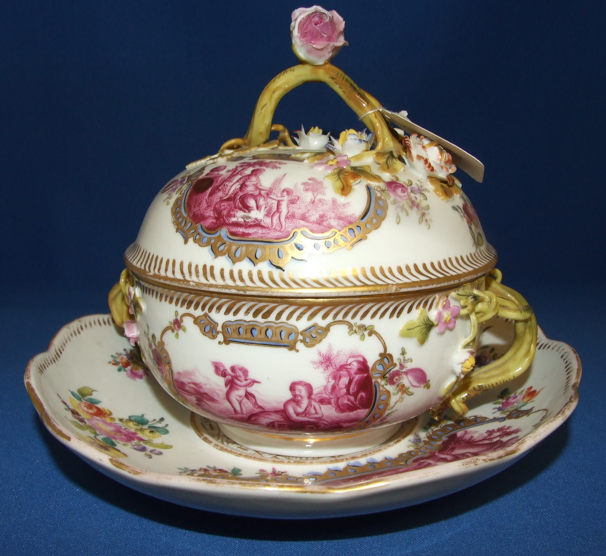 A Dresden porcelain bowl, cover and stand, decorated cherubs, flowers and foliage (some losses to