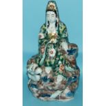 A Japanese porcelain figure, seated on a rocky mound with a dragon, 23.5 cm high