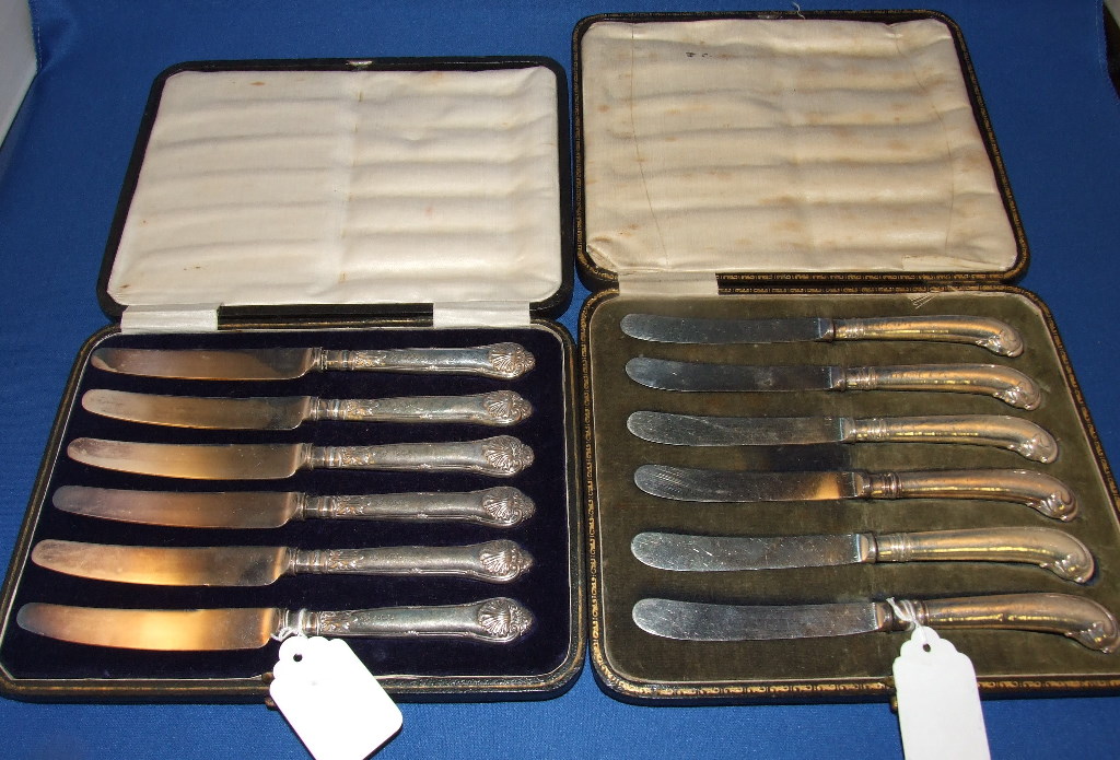 A set of silver pistol grip tea knives, loaded, and another similar set, both cased (2)