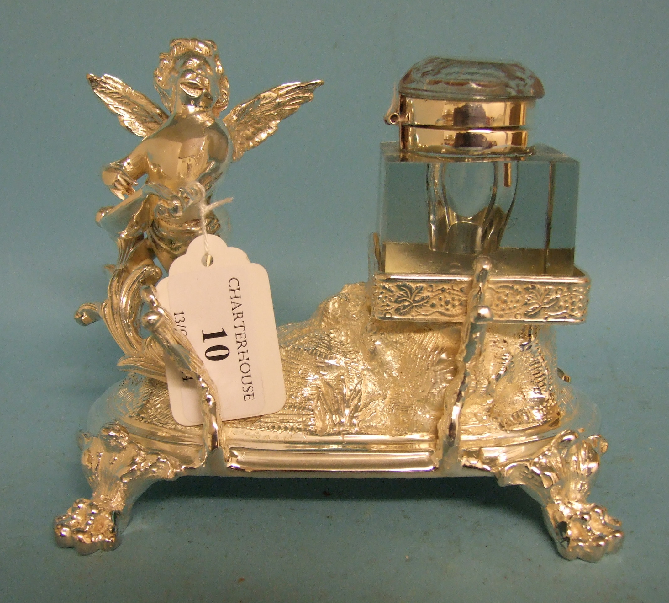 A silver plated inkwell, in the form of an angel playing a musical instrument, 15 cm wide