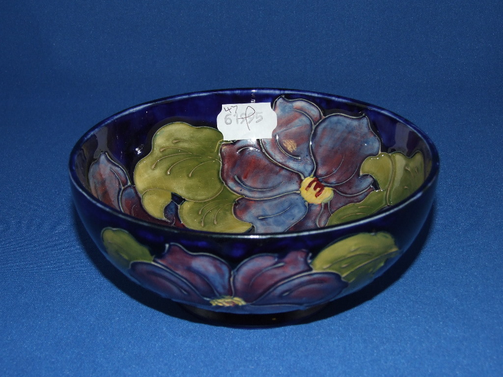 A Moorcroft pottery Clematis pattern bowl, on a blue ground, the base stamped Moorcroft Made In