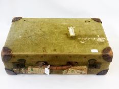 A canvas suitcase with leather corners and various travel labels