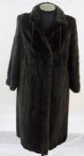 A full-length dark mink coat with leather drawstring on collar and leather bows on the sleeves