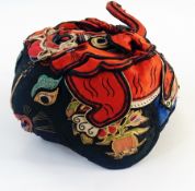 A Chinese embroidered child's hat, embroidered with an animal face on two sides