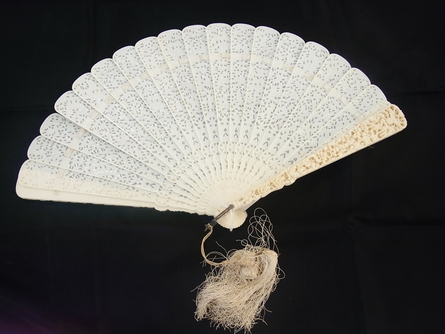 A Chinese ivory brise fan, relief carved guard sticks, in gilt lacquered box