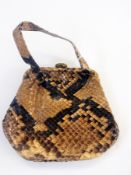 A snakeskin evening bag, possibly python, fixed frame with circular clasp and two carry handles